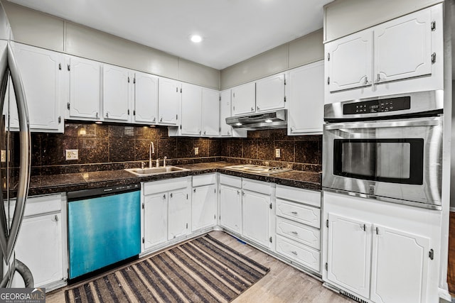 kitchen with sink, white cabinetry, light hardwood / wood-style flooring, stainless steel appliances, and backsplash