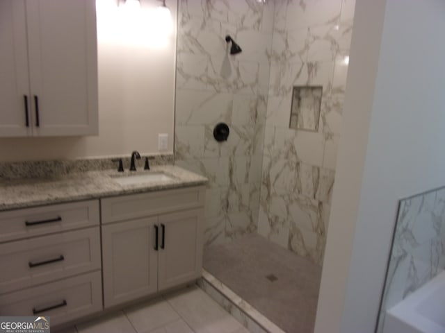 bathroom with a tile shower and vanity