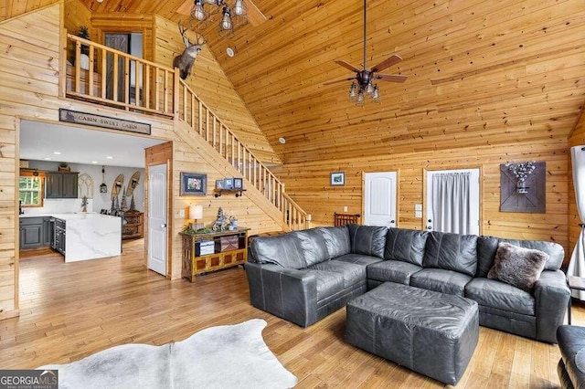 living room featuring high vaulted ceiling, wood walls, ceiling fan, and light hardwood / wood-style floors