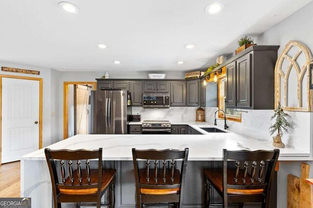 kitchen featuring gray cabinets, kitchen peninsula, light hardwood / wood-style floors, and stainless steel appliances