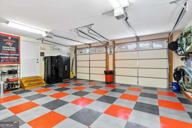 garage featuring black fridge and a garage door opener