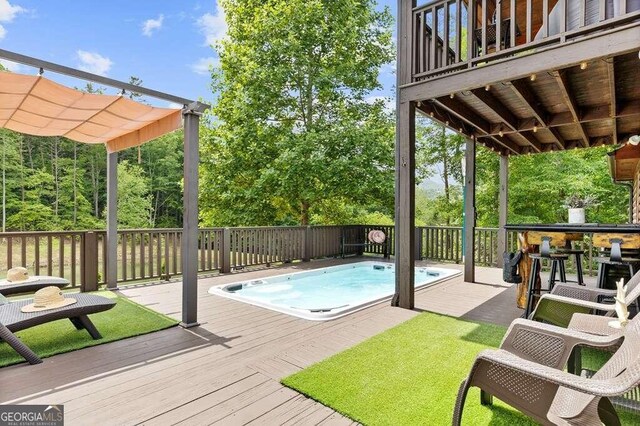 view of swimming pool with a wooden deck and a pergola