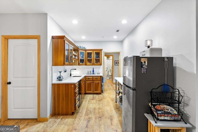 kitchen featuring stainless steel refrigerator, sink, light hardwood / wood-style flooring, and tasteful backsplash