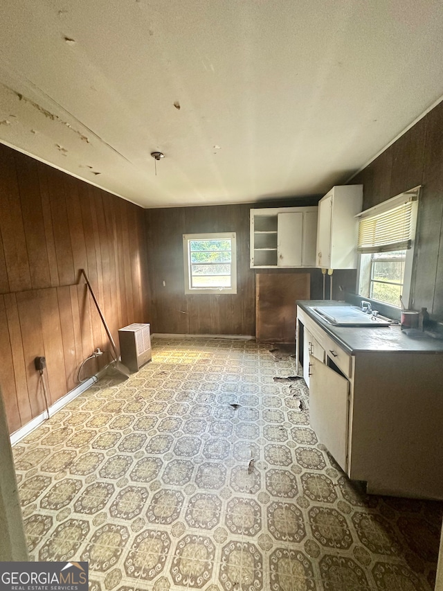 kitchen featuring a textured ceiling, wood walls, white cabinetry, and a healthy amount of sunlight