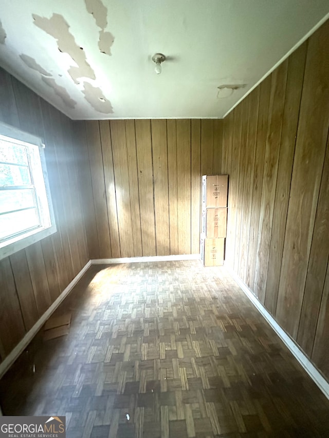 empty room featuring wood walls and dark parquet floors