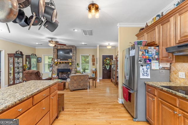 kitchen featuring crown molding, light wood-type flooring, stainless steel refrigerator, light stone countertops, and backsplash