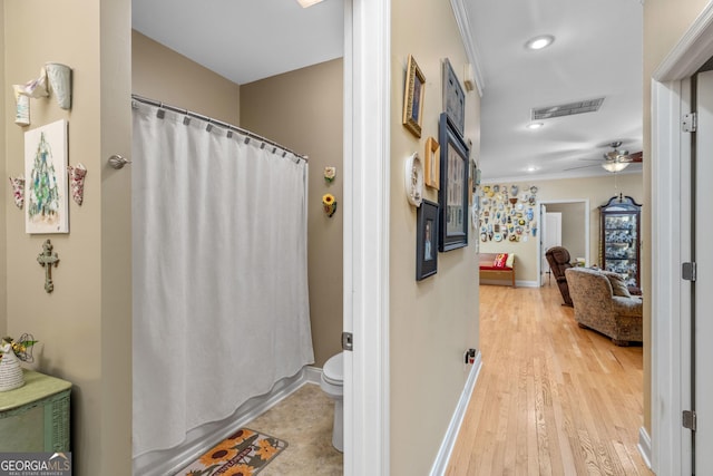 bathroom with ceiling fan, ornamental molding, wood-type flooring, and toilet