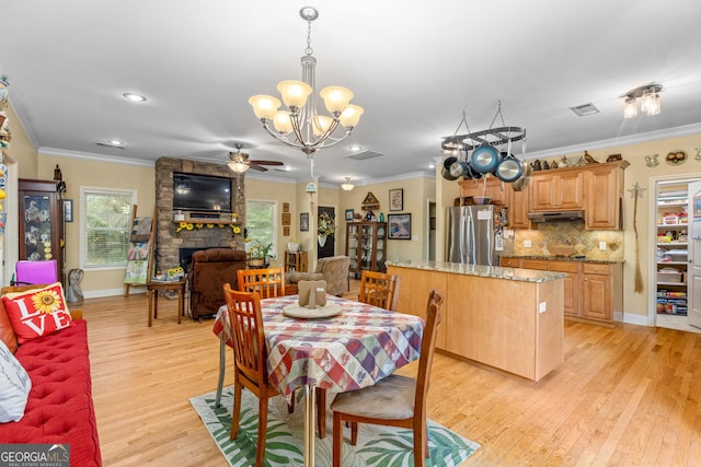 dining area with crown molding, ceiling fan with notable chandelier, a fireplace, and light hardwood / wood-style floors