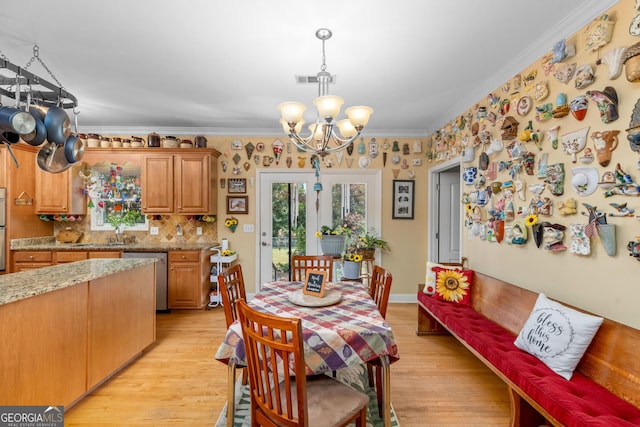 dining space featuring ornamental molding, a chandelier, and light hardwood / wood-style flooring