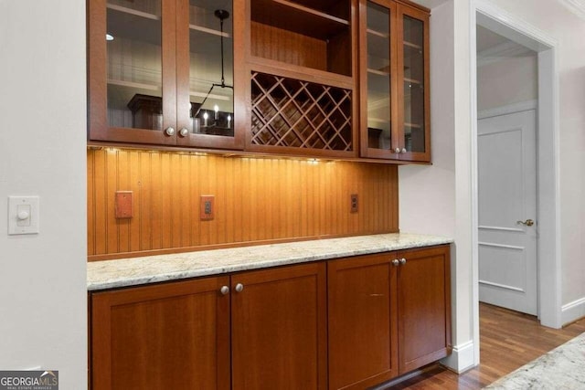 bar featuring light stone counters and hardwood / wood-style floors