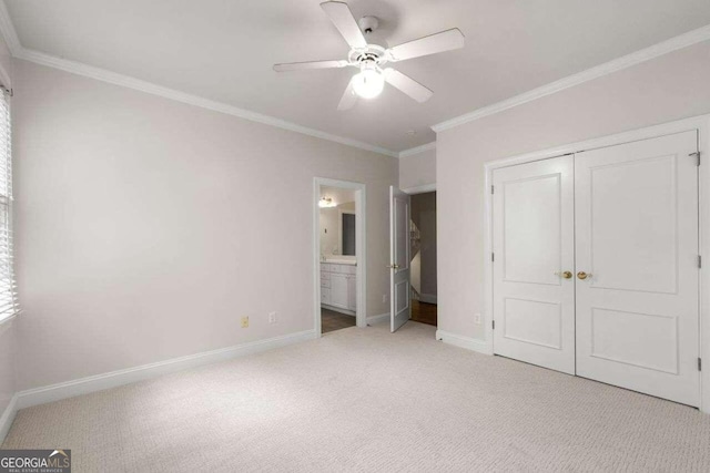 unfurnished bedroom featuring a closet, light carpet, ensuite bathroom, crown molding, and ceiling fan