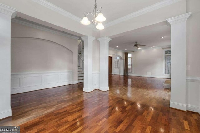 interior space featuring ceiling fan with notable chandelier, decorative columns, dark wood-type flooring, and crown molding