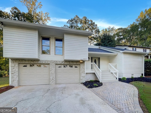 split level home with crawl space, roof with shingles, a garage, and concrete driveway
