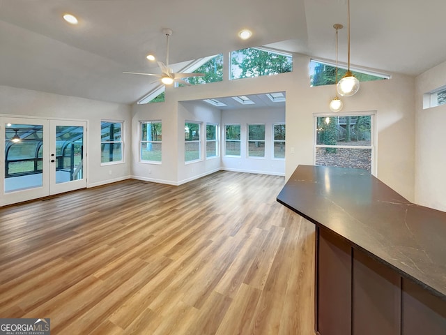 unfurnished living room featuring french doors, light wood finished floors, lofted ceiling, baseboards, and ceiling fan