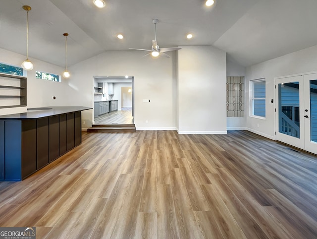 unfurnished living room with light hardwood / wood-style floors, vaulted ceiling, ceiling fan, and french doors