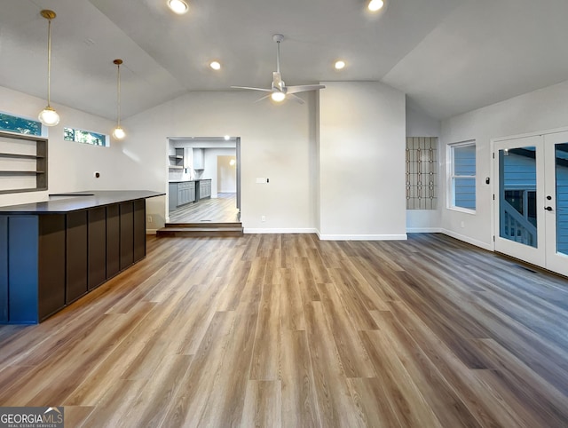unfurnished living room with light wood finished floors, baseboards, vaulted ceiling, and a ceiling fan