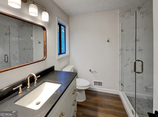 bathroom featuring a shower with shower door, vanity, a textured ceiling, toilet, and hardwood / wood-style floors