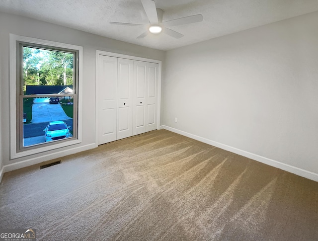 unfurnished bedroom featuring a closet, carpet floors, baseboards, visible vents, and ceiling fan