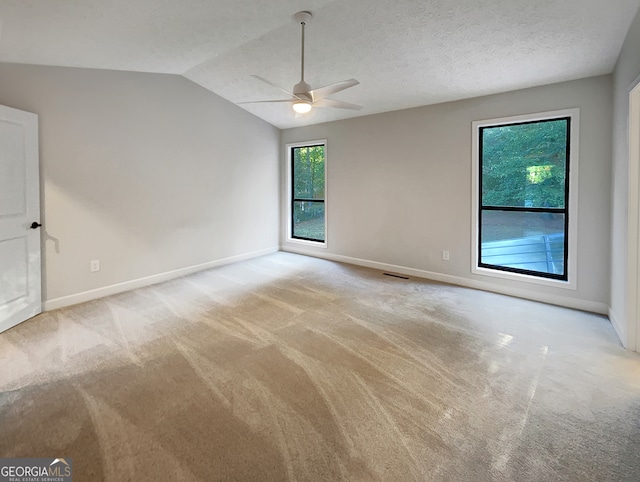 spare room with ceiling fan, a textured ceiling, light carpet, and vaulted ceiling