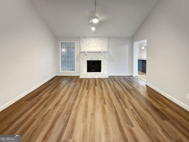 unfurnished living room with lofted ceiling, ceiling fan, hardwood / wood-style flooring, and a fireplace