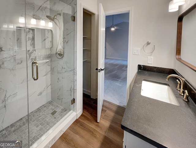 bathroom featuring wood finished floors, vanity, ceiling fan, and a shower stall