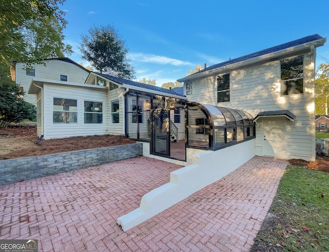 rear view of house featuring a sunroom and a patio area