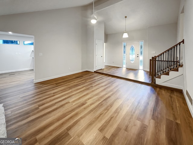 empty room with beamed ceiling, hardwood / wood-style floors, and high vaulted ceiling