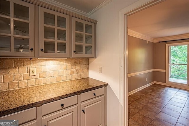 kitchen featuring ornamental molding, dark stone countertops, backsplash, and dark tile patterned floors