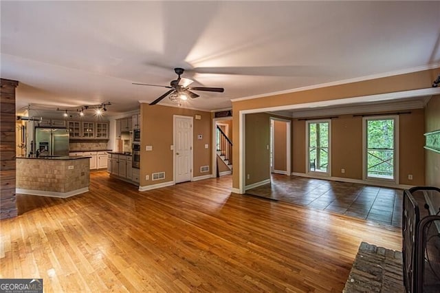 unfurnished living room featuring ornamental molding, wood-type flooring, and ceiling fan