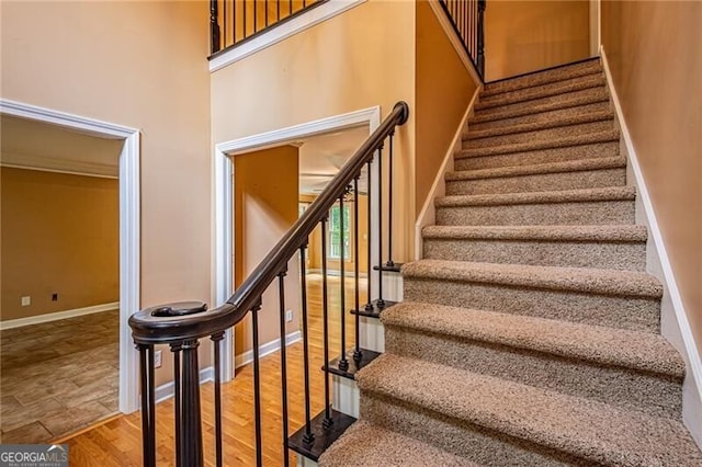 stairs with wood-type flooring and a high ceiling