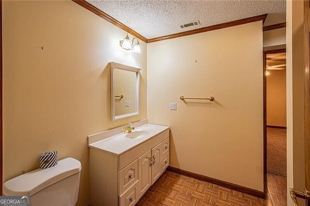 bathroom featuring vanity, ornamental molding, a textured ceiling, parquet flooring, and toilet