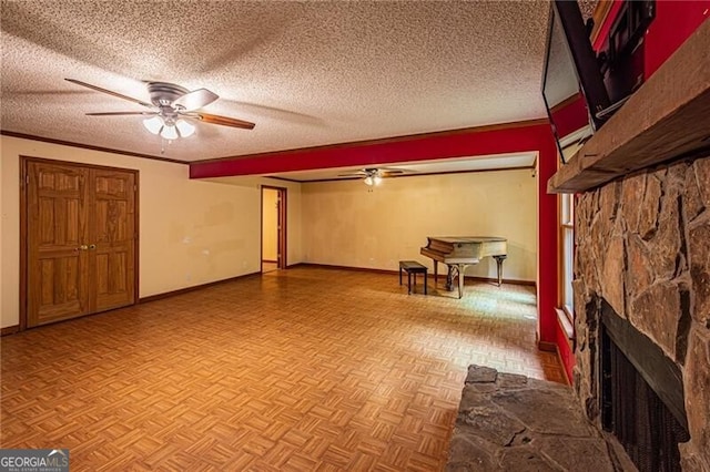 basement with a textured ceiling, ceiling fan, and a stone fireplace