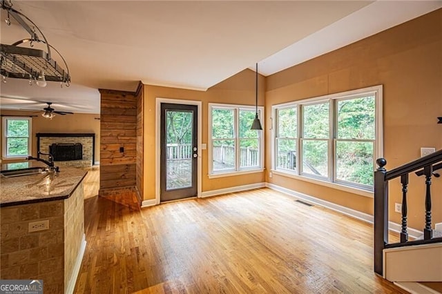 unfurnished living room with light hardwood / wood-style floors, a fireplace, sink, and a wealth of natural light