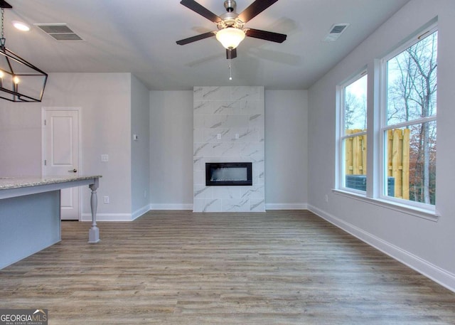 unfurnished living room featuring a high end fireplace, a ceiling fan, visible vents, and baseboards
