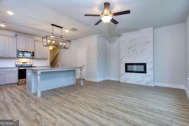 kitchen featuring a kitchen breakfast bar, gray cabinetry, light wood-style floors, and stainless steel appliances