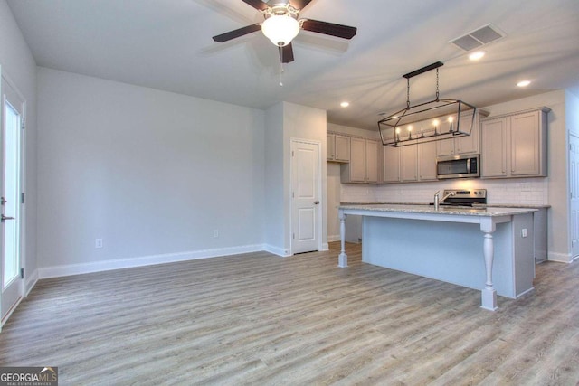 kitchen featuring light wood finished floors, visible vents, backsplash, and appliances with stainless steel finishes