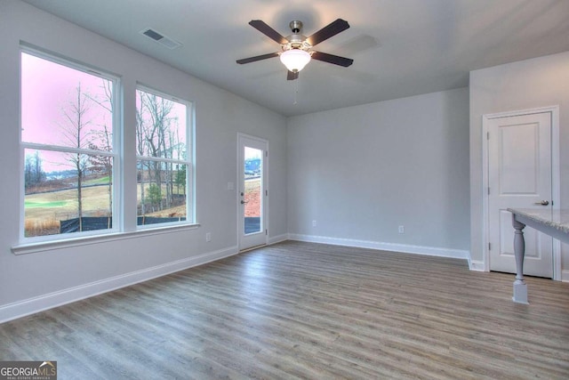 empty room featuring baseboards, visible vents, wood finished floors, and a ceiling fan