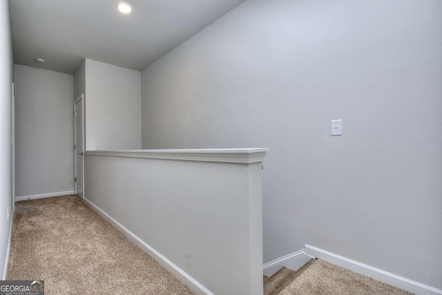 hall featuring baseboards, an upstairs landing, and carpet flooring