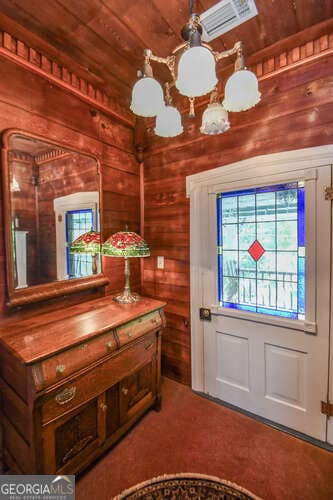 entrance foyer with wooden walls, wood ceiling, and carpet