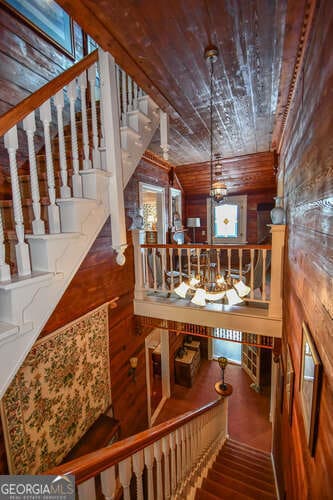 staircase featuring wooden ceiling, wood walls, hardwood / wood-style floors, and a notable chandelier