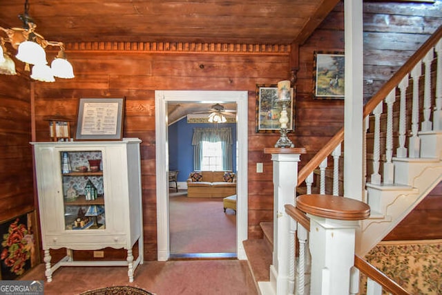 foyer with ceiling fan with notable chandelier, wood ceiling, carpet flooring, and wood walls