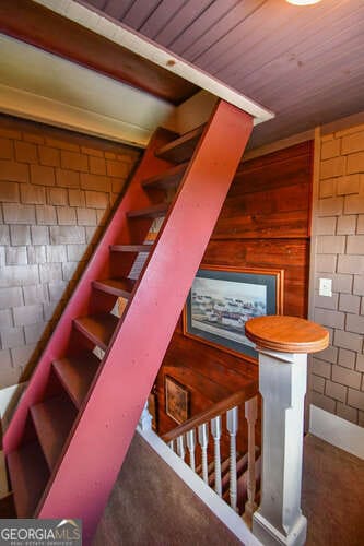 stairs featuring brick wall and wood ceiling