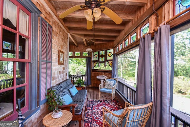 sunroom / solarium featuring beam ceiling, ceiling fan, and wooden ceiling