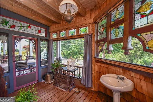 sunroom with a healthy amount of sunlight, wood ceiling, and beamed ceiling