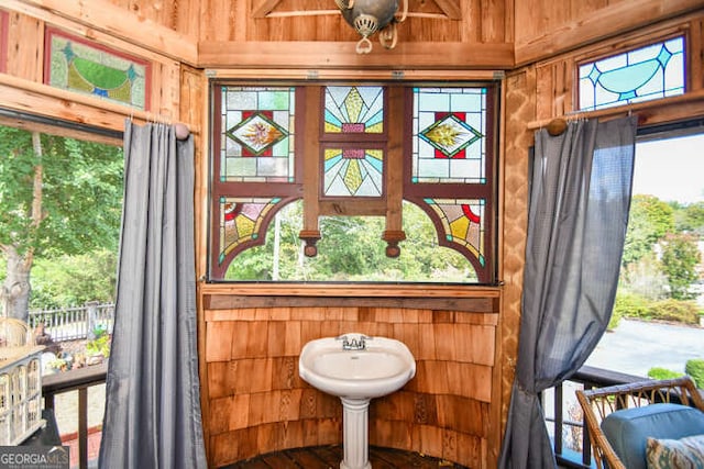 interior space with ceiling fan and wood walls