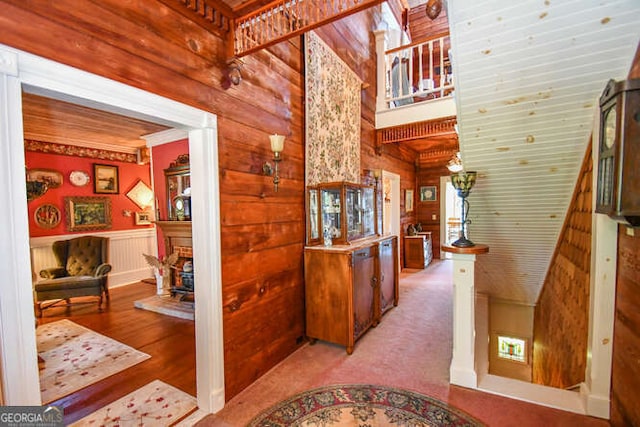 hall with light hardwood / wood-style floors and wooden walls