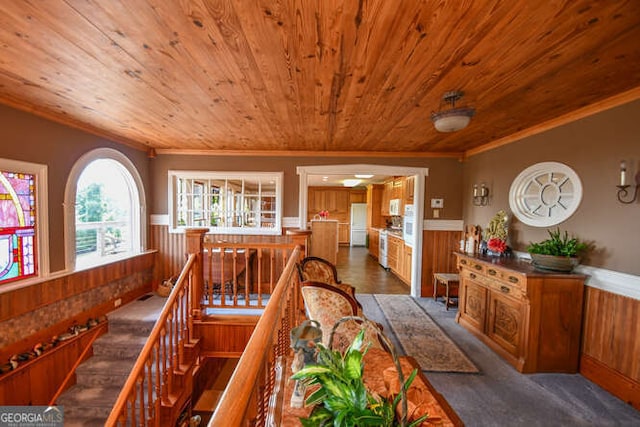 hallway featuring wooden ceiling, ornamental molding, wooden walls, and hardwood / wood-style flooring