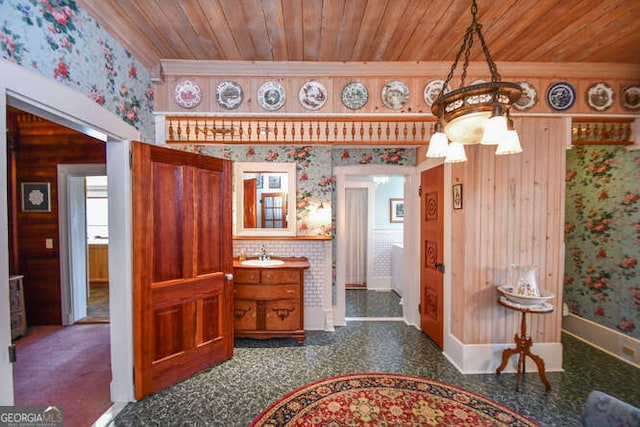 interior space featuring wood ceiling, wood walls, ornamental molding, and sink