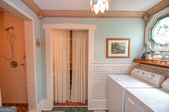 laundry room featuring tile walls, ornamental molding, and washing machine and clothes dryer