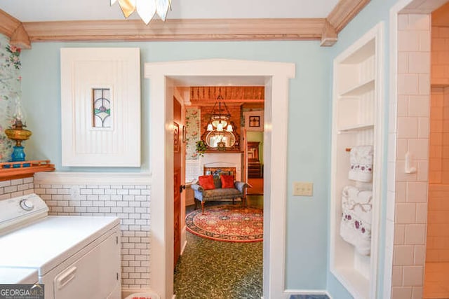 washroom featuring tile walls, ornamental molding, and washer and dryer